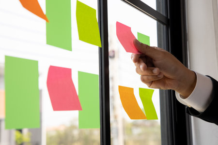 Business male hand put the Colorful notes on the wall. sticky note or paper note on the windows for...
