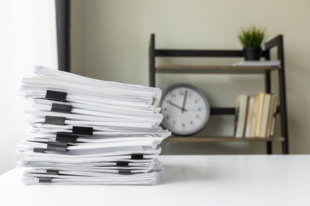 Piles of white papers work large piles of papers stacked together. On the desk in the office with black clip. Documents that are not finished. Business concept.の写真素材