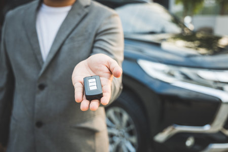 Close up businessman in suit his hands showing or giving car key for customer getting new car. Buy sell rent car concept.の写真素材