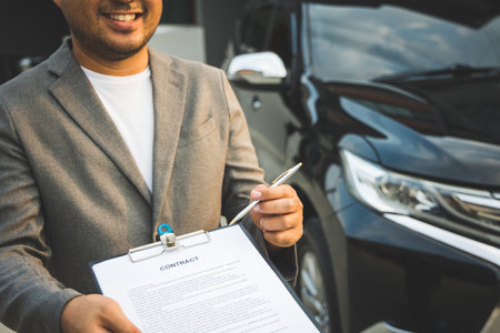 A young business man signs a luxury car leasing contract And sign a car insurance purchase contract on the documents according to the agreementの写真素材