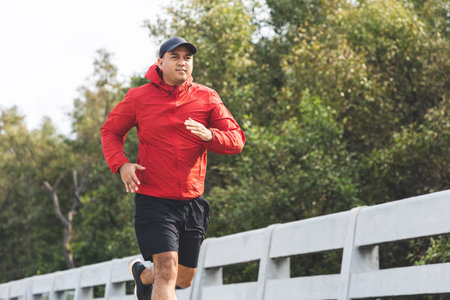 Young asian man wearing sportswear running outdoor. Portraits of Indian man jogging on the road....