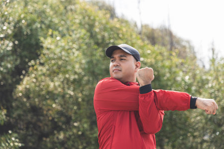 Young asian man wearing sportswear running outdoor. Portraits of Indian man stretching arm before running on the road. Training athlete work out at outdoor concept.の写真素材