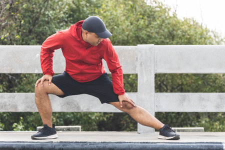 Young asian man wearing sportswear running outdoor. Portraits of Indian man stretching leg before...
