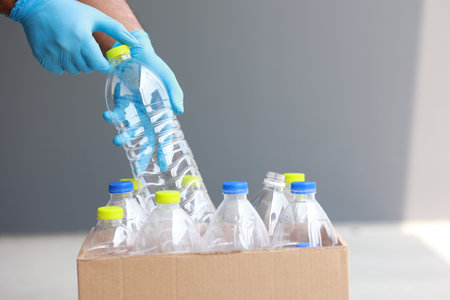 Man's hand in blue glove holding plastic bottles of water. Close up.の写真素材