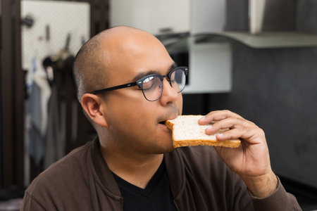 A young asian man eating breakfast Whole Wheat Bread Healthy breakfast It has good carbohydrates and vitamins. Fast food to eat in the morning before going to workの写真素材