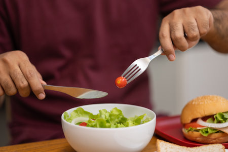A young man eating breakfast. Breakfast set includes bread, bacon, salad and sausage.の写真素材