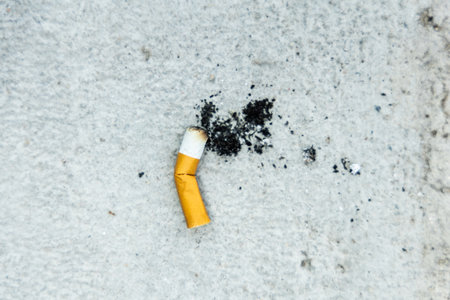 The smoking cigarette is left on the floor. Cigarette butt on the floor.の写真素材