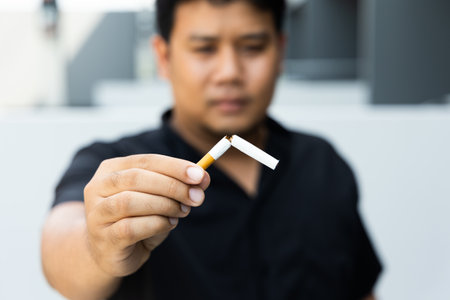 The young man used his hand to break a cigarette into two. He wants to quit smoking for good health. world tobacco day.の写真素材