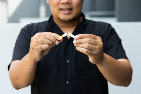 The young man used his hand to break a cigarette into two. He wants to quit smoking for good health. world tobacco day.の写真素材