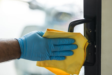 A young man cleans the handrail by spraying a cleaning agent to kill viruses for good hygiene. He...