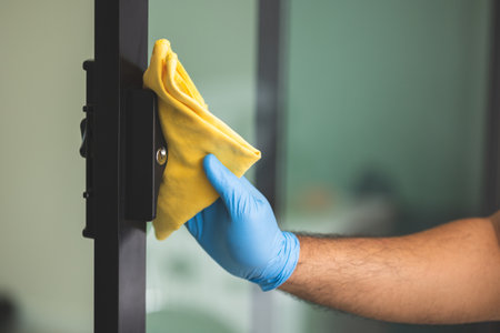 A young man cleans the handrail by spraying a cleaning agent to kill viruses for good hygiene. He put on rubber gloves and wipes.の写真素材