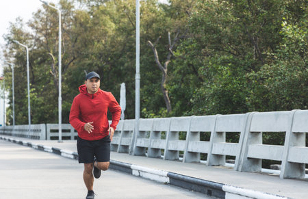 Young asian man wearing sportswear running outdoor. Portraits of Indian man jogging on the road....