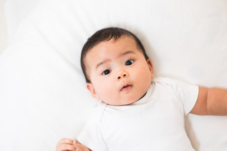 A cute baby wearing a white dress Stay with parents in the houseの写真素材