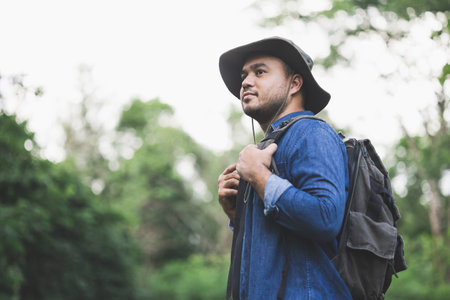 Young handsome man with a backpack is walking alone the road. Man is looking forward to an...