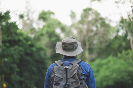 Young man with a backpack is walking alone the road. Man is looking forward to an interesting travelling.の写真素材