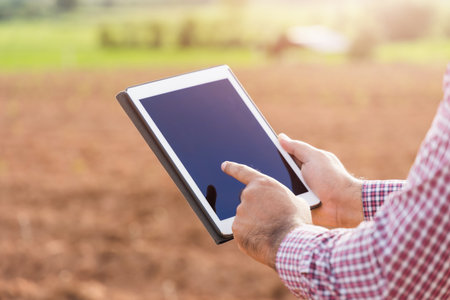 Smart farmer using a technology for studying and development agricultural. The farmer using tablet for tests the growth quality of seedling.の写真素材