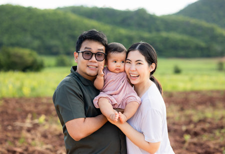Happy asian family father mother child daughter on nature background . Parents hug little baby in...