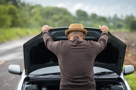 Young asian has broken down car. He open hood and check the engine. He feeling upset and stressed. Car broken on the side of the roadの写真素材