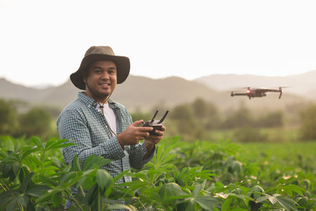 Asian farmer using drone flying navigating above farmland. A young farmer controls a drone in a...