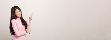 Beautiful asian woman look into blank space. Smiling female wearing pink shirt on isolated white background. Attractive Teenager girl looking at empty space for text feeling excited and surprised.の写真素材