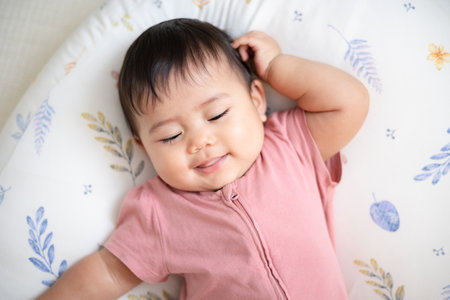 An Asian girl about 1 year old. Playing in the living room in the house. A cute baby wearing a pink...