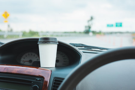 A cup of hot coffee put on the car console. Drinking coffee while travel by car.の写真素材