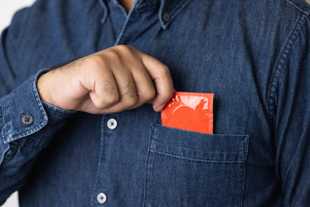 The young man took the condom out of his pocket. Campaign for safe sex and contraception. Close up male hand holding the condom.の写真素材