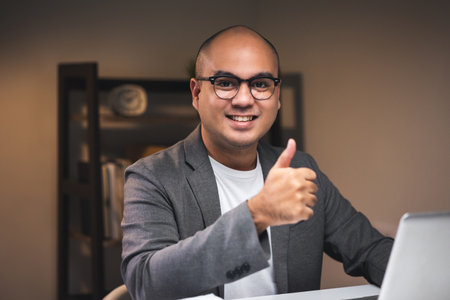 Young asian businessman working with laptop computer in the dark office at night. Attractive...