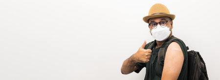 Vaccinated. Traveler asian man wearing mask showing arm after coronavirus Vaccination isolated white Background. Backpacker Indian man getting a vaccination covid-19 immunizationの写真素材