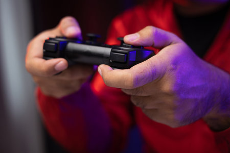 Close up male hands holding joystick game console. Young man playing video game online. Indian man...