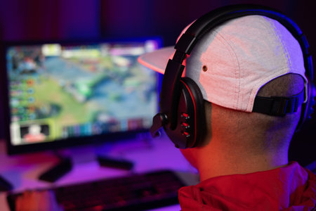 Rear view Play video computer pc. Young man sitting on chair in game station. Happiness Streamer...