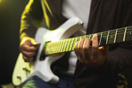 Close up hands young man rocker playing electric guitar on stage live in concert. With neon light....
