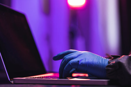 Close up hands Hackers. Hacking to steal important information. Use a computer to release malware viruses Ransom and harass organizations. He sitting in the dark room with neon lightの写真素材