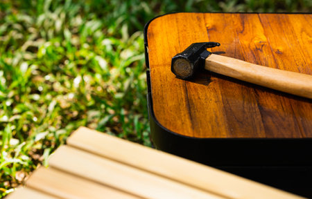 Hammer and camping accessory on wood table. Equipment for camping in forest. In summer with sunlight.の写真素材
