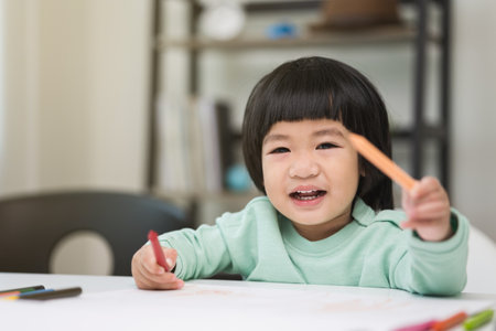 Happy asian boy painting with crayon and colored pencil in living room at home. Little boy doing homework Practice the skills of drawing and painting.の写真素材