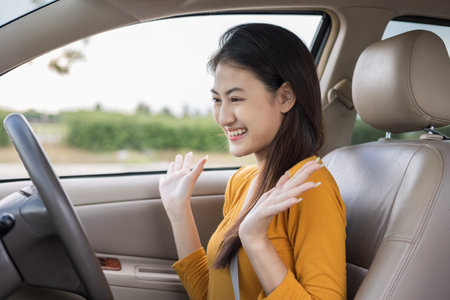 Wow. Young beautiful asian women getting new car. she very happy and excited. she sit and touching every detail of car. Smiling female driving vehicle on the roadの写真素材
