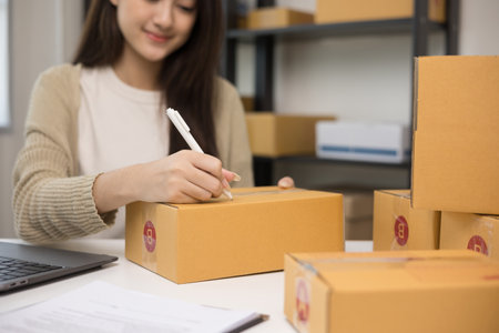 Young asian business woman writing address to sending product to customer. Online business working...