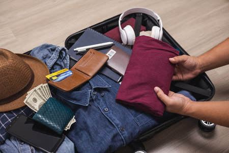 Top view Close up male hands organize luggage. Put clothes and pants in trolley bag and prepare to...