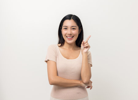 Beautiful asian woman thinking. Smiling female standing pose on isolated white background. Attractive Teenager girl around 25 looking at empty space for text feeling excited and thinking.の写真素材