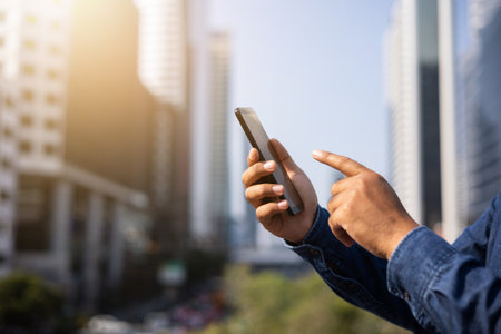 Businessman hand holding using smartphone on urban city background.の写真素材