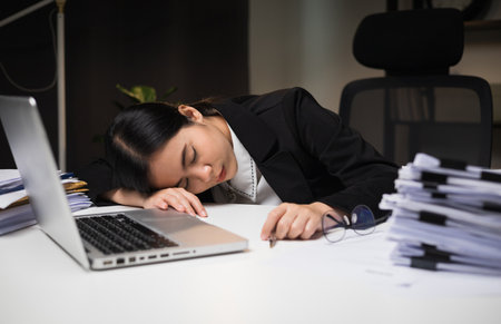 The business woman worked so hard that she fell asleep at her desk. Working overtime because it's almost time for the deadline. She was tired from job and took a nap.の写真素材