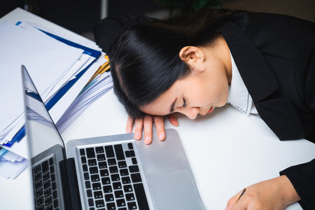 The business woman worked so hard that she fell asleep at her desk. Working overtime because it's almost time for the deadline. She was tired from job and took a nap.の写真素材