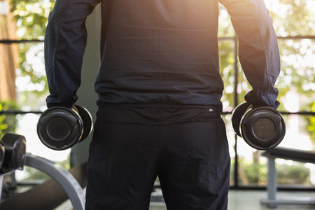 Young Fitness man with dumbbell in gym. Guy weight training wearing sportswear. Asian man exercise...