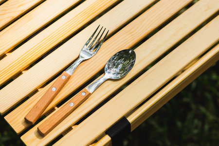 Cutlery and camping accessory on wood table. Equipment for camping in forest. In summer with sunlight.の写真素材