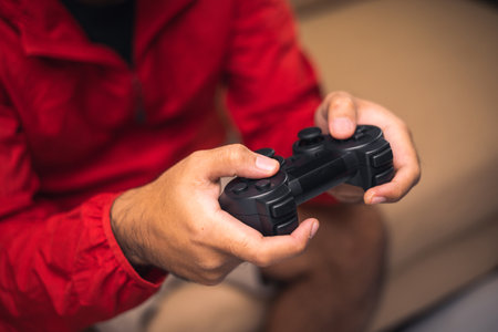 Close up male hands holding joystick game console. Young man playing video game online.の写真素材