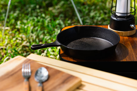 Iron pan and camping accessory on wood table. Equipment for camping in forest. In summer with sunlight.の写真素材