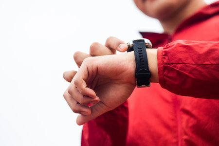 Young man wearing sportswear red jacket using Smart Watch Showing Heart Rate Monitor. Technology for...