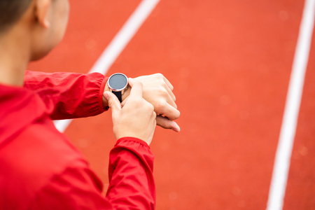 Young man wearing sportswear red jacket using Smart Watch Showing Heart Rate Monitor. Technology for health and sport mode. Exercise and take statistics to develop your potential.の写真素材