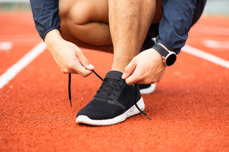 Hands man runners tie shoelaces prepared to run on track. Young asian man wearing sportswear running sport stadium.Training athlete work out at outdoor concept.の写真素材