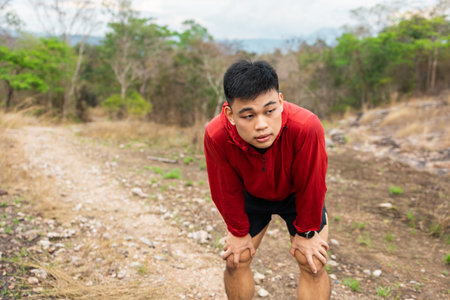 A young trail runner runs long distances until he gets tired. He rested for a moment and continued running until the finish line.の写真素材